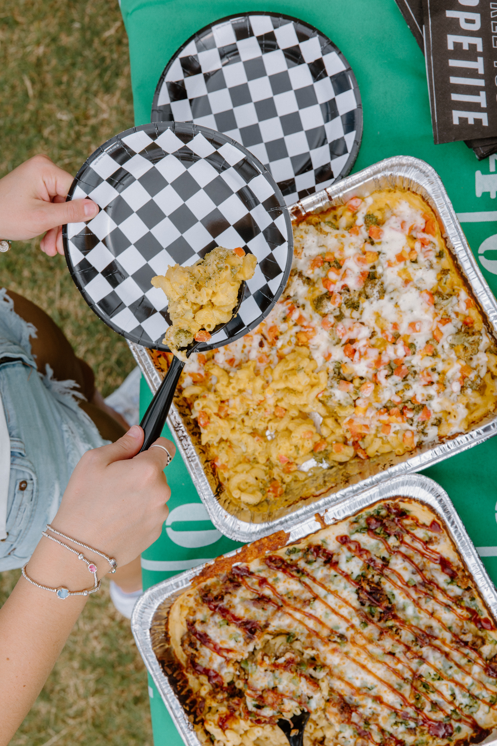 Party-size trays of mac and cheese being served outdoors